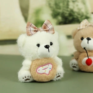 Gros plan d'un ours en peluche blanc tenant un accessoire de beignet rose brodé