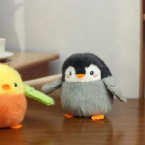 Close-up of a cute penguin plush keychain with soft fur and pink blush embroidery