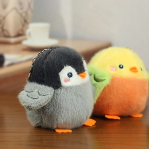 Detailed close-up of plush penguin and chick keychains with metal rings on wooden table