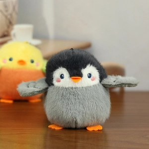 Detailed view of plush penguin and sparrow charms on a wooden surface with soft lighting