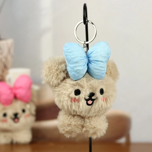 Detailaufnahme von süßem Plüsch-Teddybär mit großer blauer Satinschleife und Stickerei
