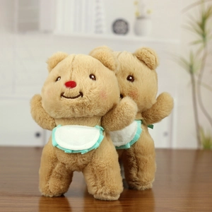 Plush butter bear doll pendants in light brown with white bibs on wooden table