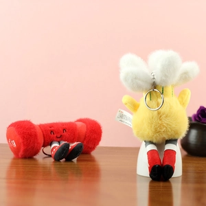 Détail de porte-clés en peluche haltère rouge et fleur jaune sur une surface en bois
