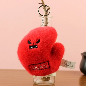 Détail d'un porte-clés gant de boxe en peluche rouge avec broderie et anneau en métal
