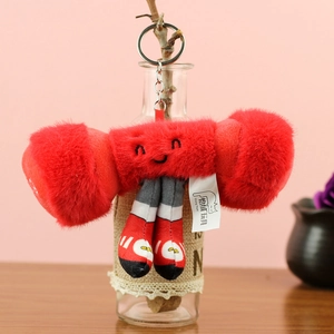 Détail d'un porte-clés peluche haltère rouge avec visage brodé et anneau argenté