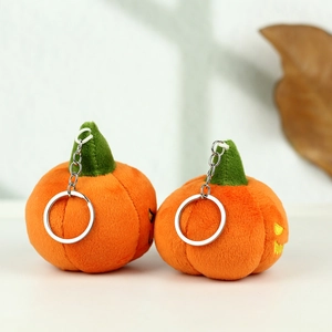 Detail of two orange plush pumpkin keychains with green stems and metallic rings