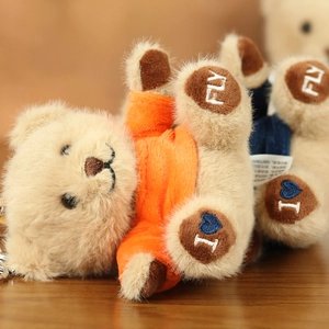 Detail of plush teddy bear pendant featuring a soft brown hoodie and foot embroidery