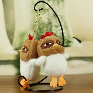 Close-up of two cute plush chicken pendants with fluffy brown heads and soft white bodies