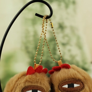Detail of plush chicken charms with red combs and gold bead chains on a display stand