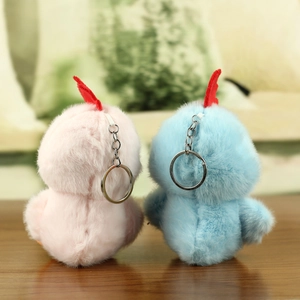 Macro view of blue and pink plush chicken keychains on a wooden table with silver rings