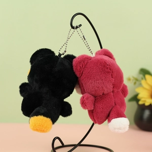 Cute plush bear keychains in black and burgundy hanging on a minimalist display stand