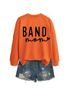 Detail view of an orange BAND mom crewneck sweatshirt paired with ripped denim shorts
