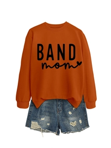 Flat lay of an orange crew neck BAND mom sweatshirt with distressed blue denim shorts