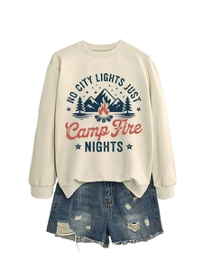 Flat lay of cream sweatshirt with camp fire graphic and ripped denim shorts for outdoor look