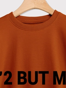 Gros plan d'un sweat à col rond caramel avec bord-côte et détail d'impression graphique noir