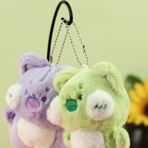 Macro detail of soft lavender and green plush cat keychains with embroidered faces