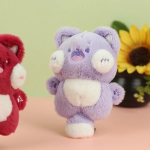 Close-up of soft plush cat keychain in purple and red colors with fluffy texture