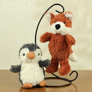 Detail of plush peanut penguin and fox toys on a wooden table with soft texture