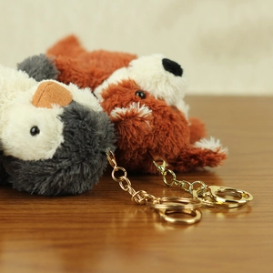 Close-up of cute plush penguin and red panda keychains with gold metal clasps