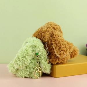 Dettaglio di portachiavi a coniglietto di peluche verde e marrone con moschettoni oro