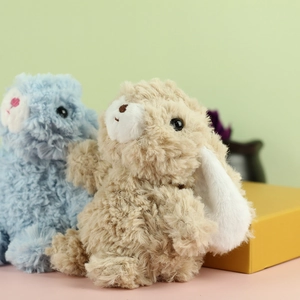 Dettaglio di portachiavi a forma di coniglio in morbido peluche beige e blu chiaro