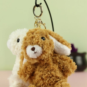 Dettaglio di portachiavi a forma di coniglio in peluche marrone e bianco con anelli dorati