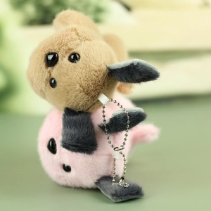 Close-up of plush dog keychains in pink and light brown with soft texture and bead chains