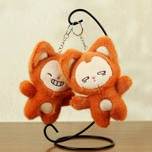 Close-up of two cute orange plush fox keychains with embroidered smiles and silver hooks