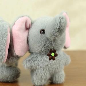 Close-up of a plush elephant toy with gray fur, pink inner ears, and a small brown flower
