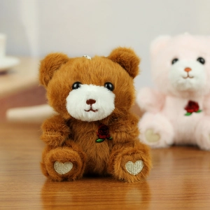 Close-up of soft plush teddy bear charm featuring an embroidered rose and heart details