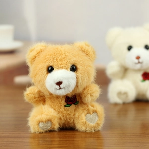 Close-up of plush teddy bear with red rose embroidery and heart-shaped paw details