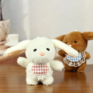 Close-up of cute plush bunny charms with lace-trimmed checkered bibs in soft fur