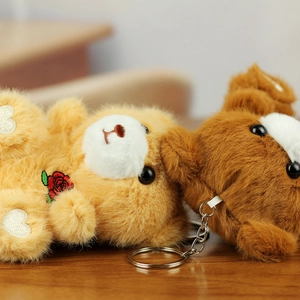 Close-up of plush bear keychains with rose embroidery and soft texture details