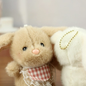 Close-up of cute plush bunny charms with soft fur and decorative checkered bibs
