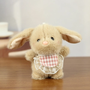 Close-up of cute plush bunny keychain with pink plaid bib on wooden background