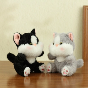 Close-up of cute plush cat keychains in black and grey sitting on a wooden table