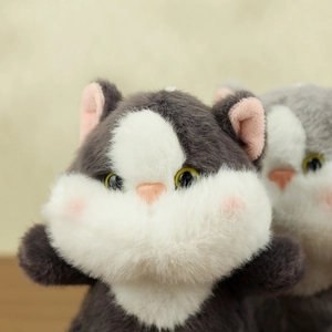 Macro shot of cute grey and white plush cat charm with soft fluffy texture and pink cheeks