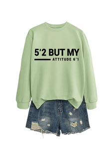 Détail du sweat-shirt vert clair avec slogan et short en jean déchiré au style vintage