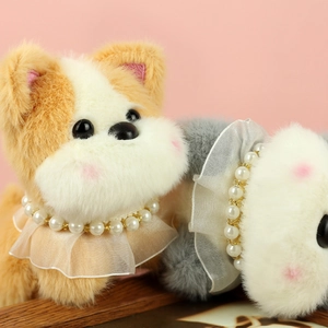 Gros plan de pendentifs chiots en peluche avec colliers de perles et froufrous en dentelle