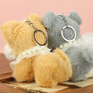 Gros plan de porte-clés chien en peluche jaune et gris avec colliers de perles sur bois