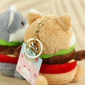 Detail of plush hamburger cat keychain with golden metal clasp and decorative tag
