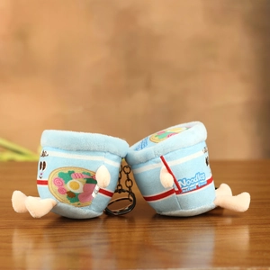 Detail of plush seafood ramen cup charms with metal keychains on a wooden desk