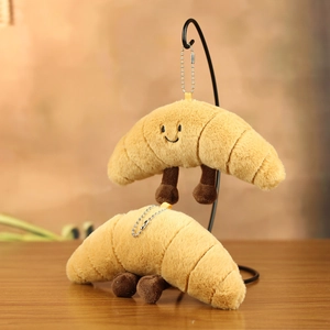 Detail of cute plush croissant keychain with embroidered face and silver chain