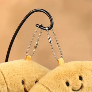 Close-up of plush yellow croissant pendant with metal bead chain on a display stand