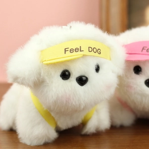 Nahaufnahme eines weißen Plüschwelpen-Anhängers mit gelbem FeeL DOG Hut und gelben Trägern