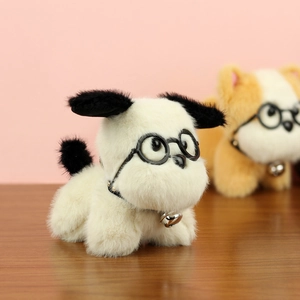 Gros plan d'un chiot en peluche blanc avec lunettes, oreilles noires et clochette argent