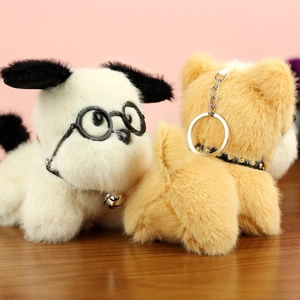 Vue détaillée de deux porte-clés chien en peluche avec lunettes sur une table en bois