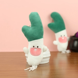 Macro view of cute plush green onion pendant with funny face embroidery and fringe root detail