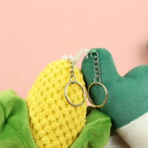 Close-up of cute plush corn and green vegetable charms with silver metal keychains