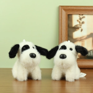 Cute spotted plush dog keychains with soft white fur and black spots on wooden surface